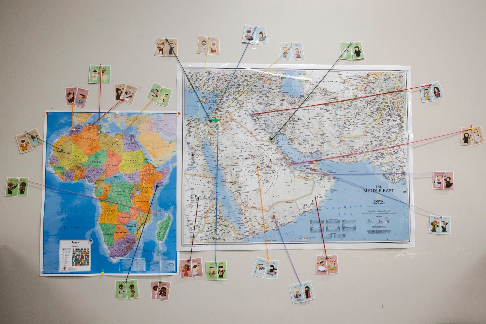 Inside the camp classroom, a bulletin board has a map with yarn tracing different nationalities to their respective countries.