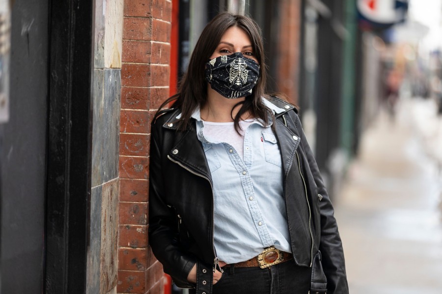 Restaurant worker Allison June Palmer, wearing a black mask, stands on a sidewalk.