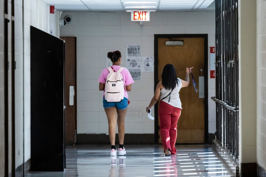 student and teacher walk down school hallway