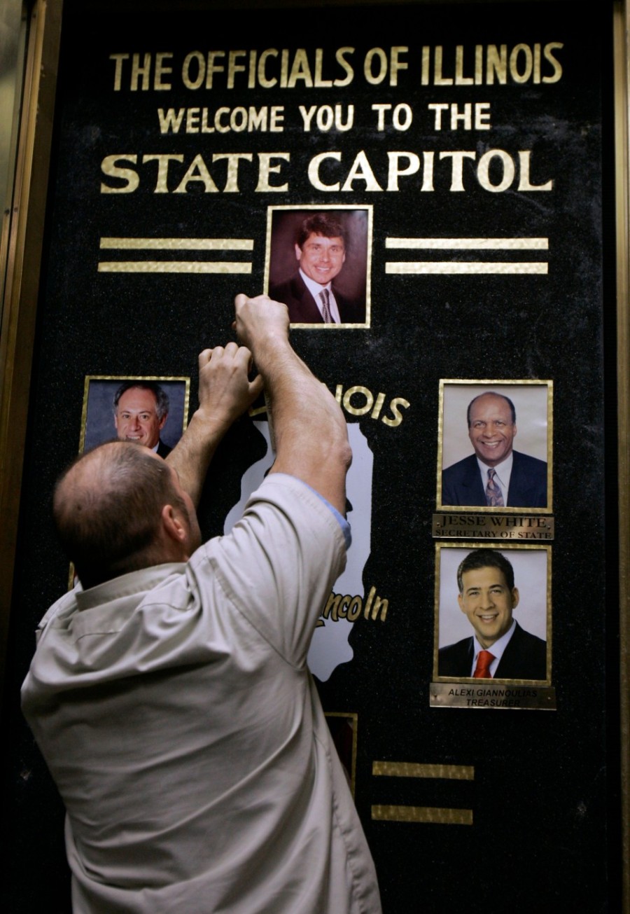 An Illinois state worker removes a board containing the photo of Illinois Gov. Rod Blagojevich after Blagojevich was removed from office Thursday, Jan. 29, 2009, in Springfield, Ill.