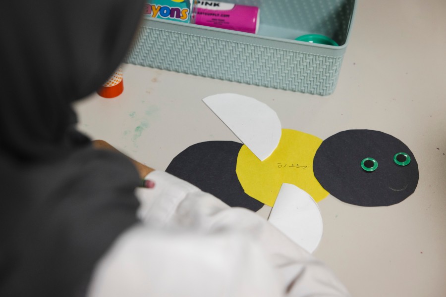 Children make a construction paper bee as part of an Arabic lesson.