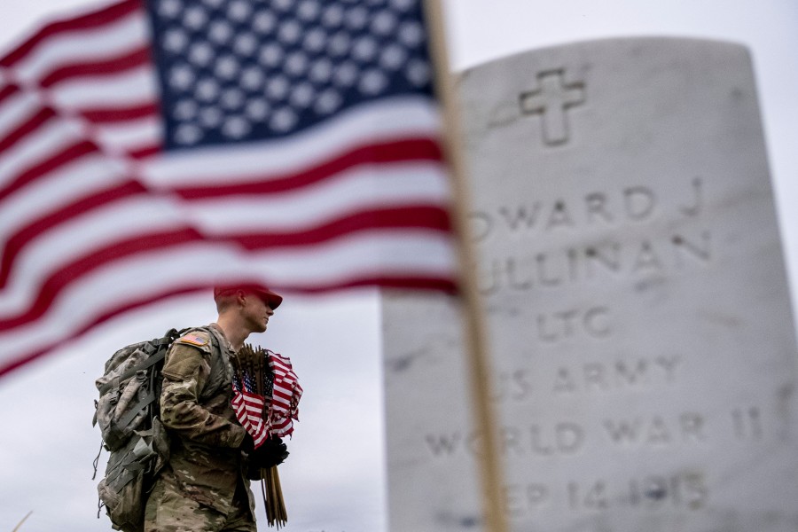 A member of the 3rd U.S. Infantry Regiment places flags in front of each headstone for “Flags-In” at Arlington National Cemetery